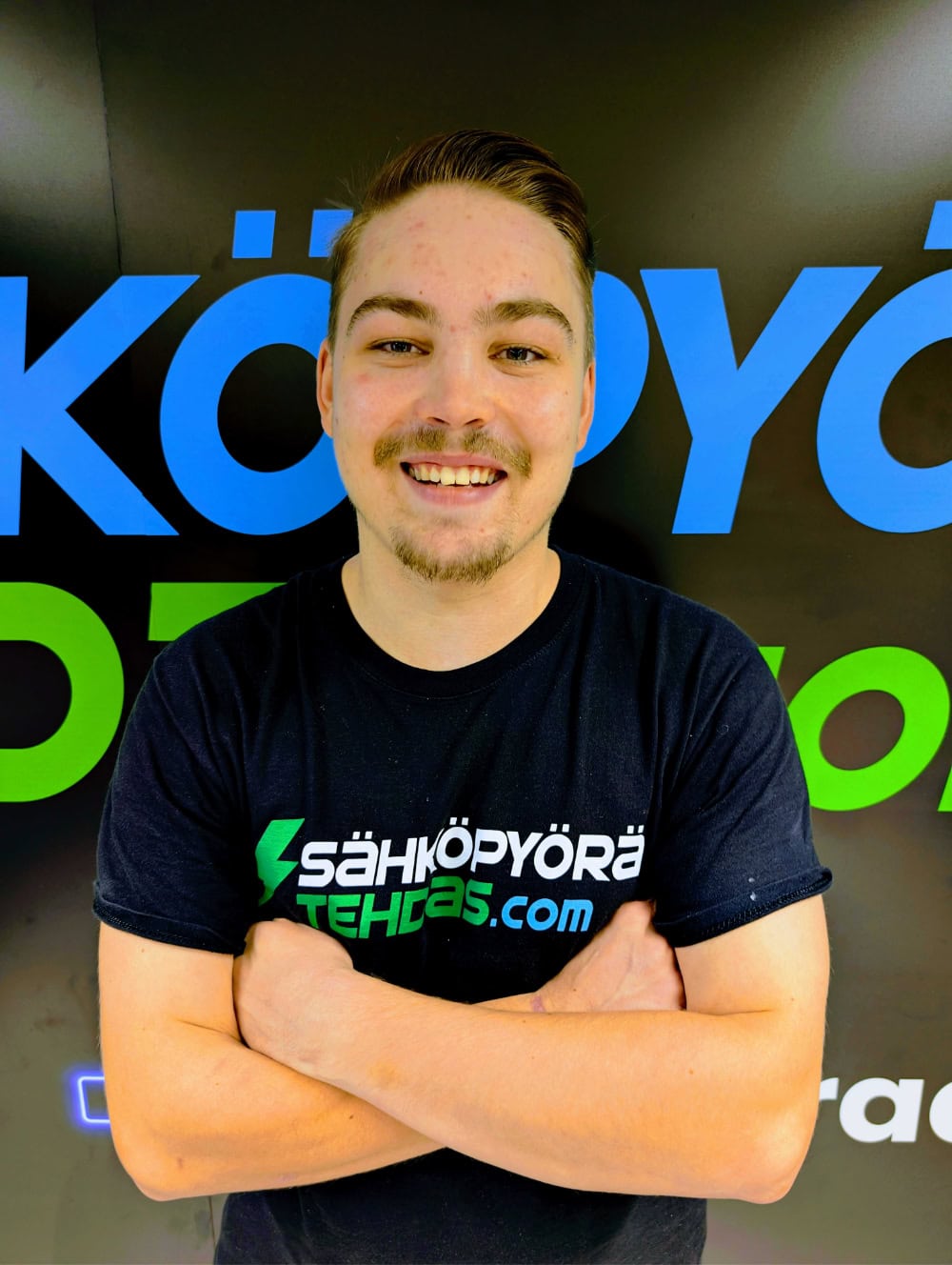 Iloinen myyjä pyöräkaupassa esittelee sähköpyöriä valikoimasta.